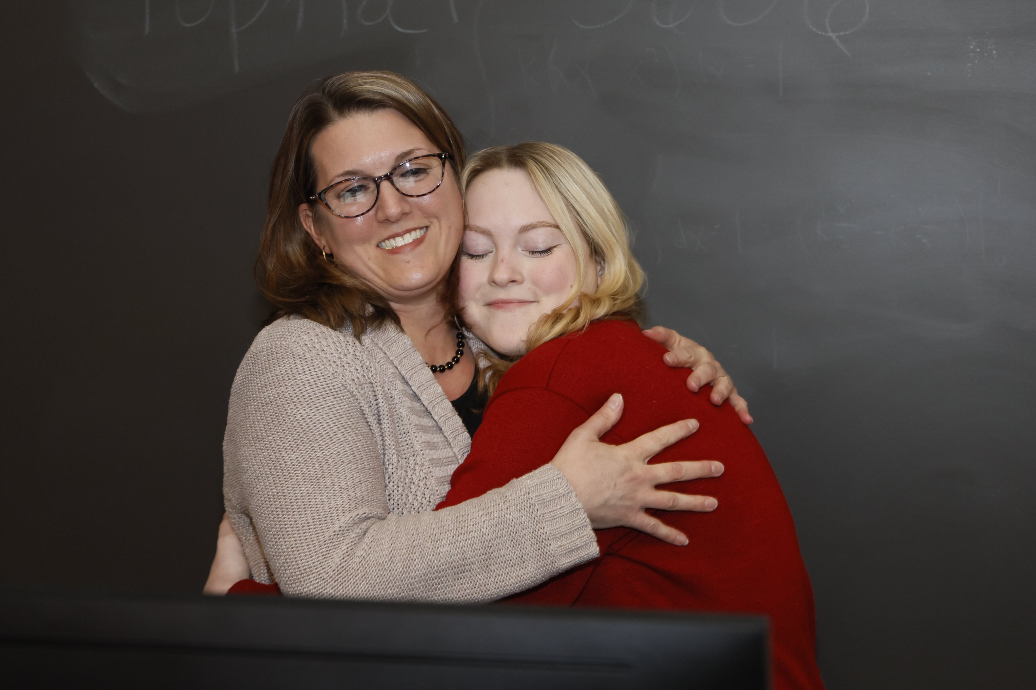 Angela Collene hugging her daughter at a graduation ceremony