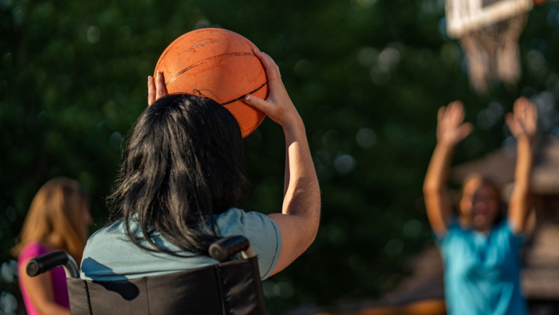 student in wheel chair shooting basketball
