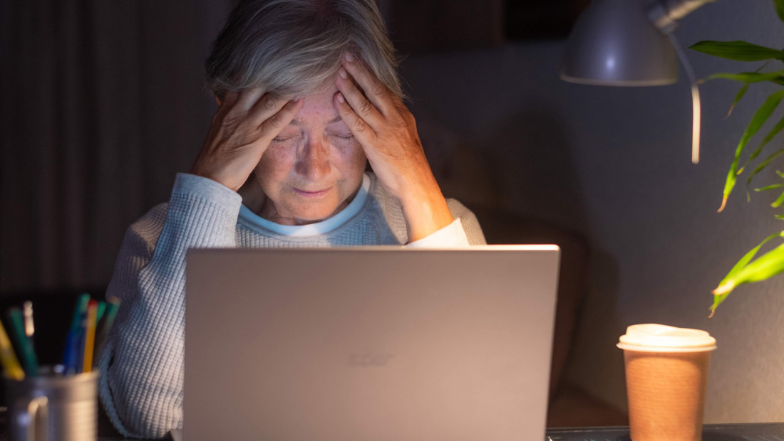 older women alone at her computer looking stressed