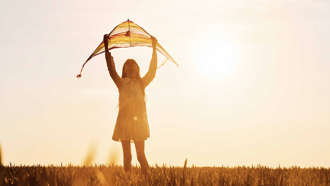 child holding a kite in the sunset