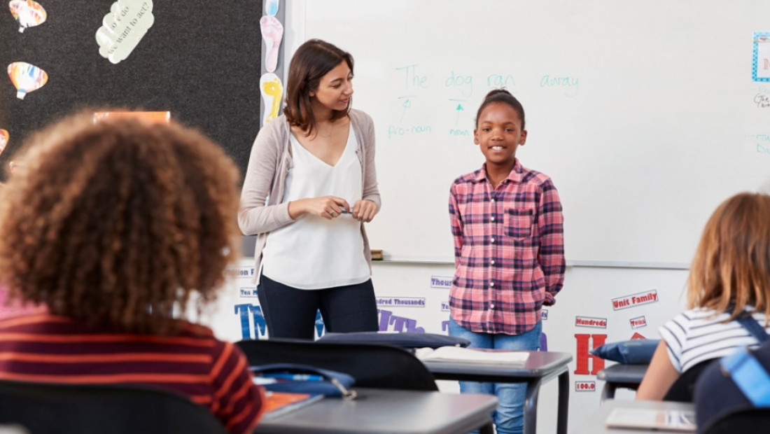 elementary student and teacher in front of class