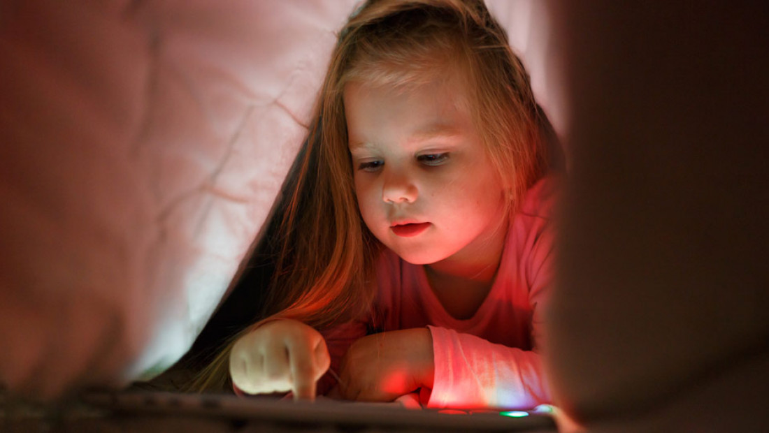 child reading under blanket
