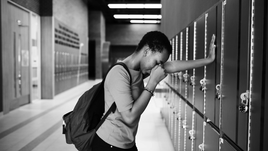 boy in school leaning against lockers in black and white