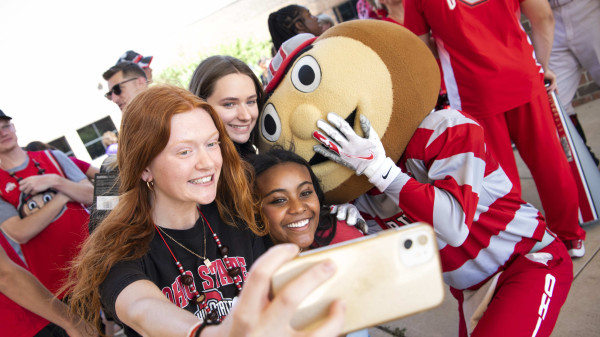 First year Ohio State students with Brutus the Buckeye at a tailgate taking a selfie.