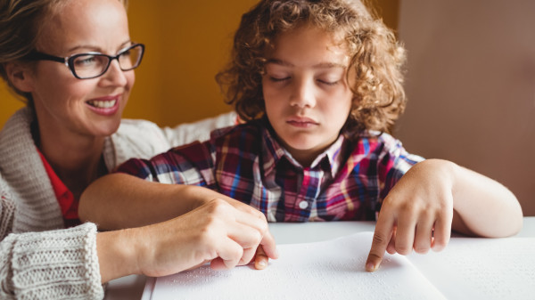 Teacher helping student read braille