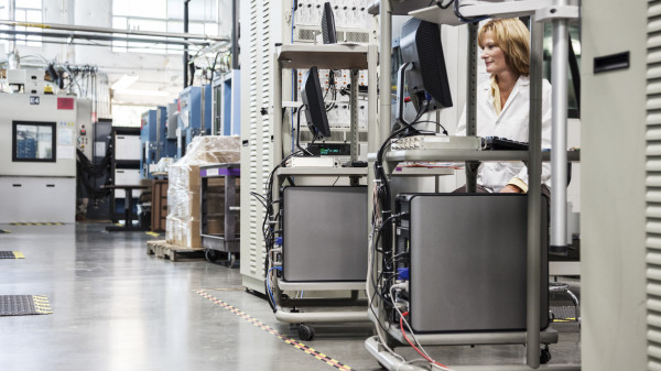 A caucasian female technician working over a problem in a technical research and development site.