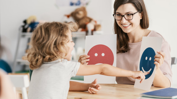 Woman therapist with child using emotion cards