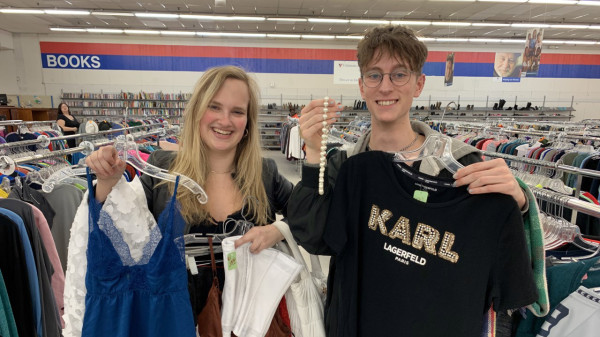 Ohio State students holding items of thrifted clothing in thrift store