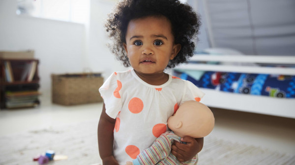 child in playroom holding baby doll