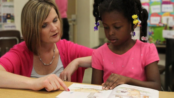 Teacher pointing to a picture on a book for a student