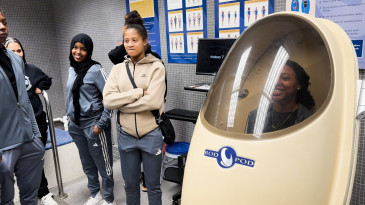 Ohio State students look on as a student is in an Exercise Science lab uses a Bod Pod