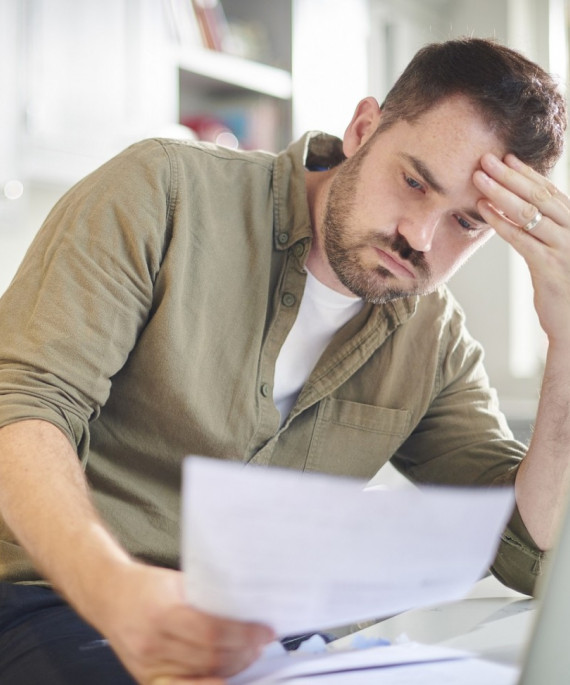 man reviewing documents are kitchen counter with open laptop