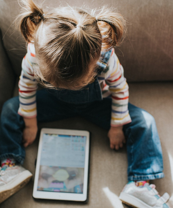 Young child sitting on couch looking at an iPad