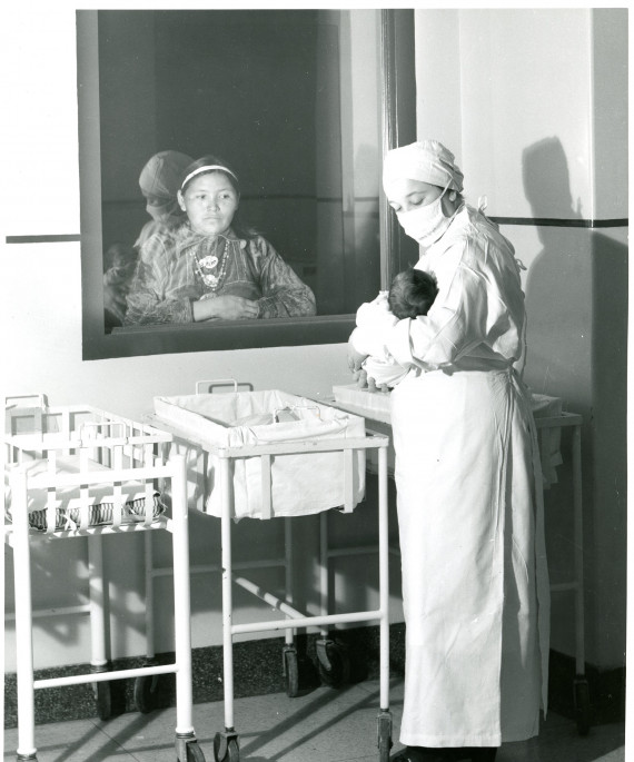 Native American mother looking through hospital window at her child