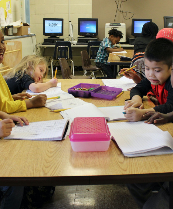 School children sitting at shared table doing a workbook