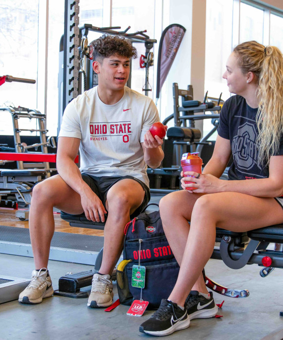 Ohio State students sitting on lifting bench in the gym