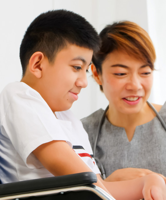 physical therapist talking to a disabled boy