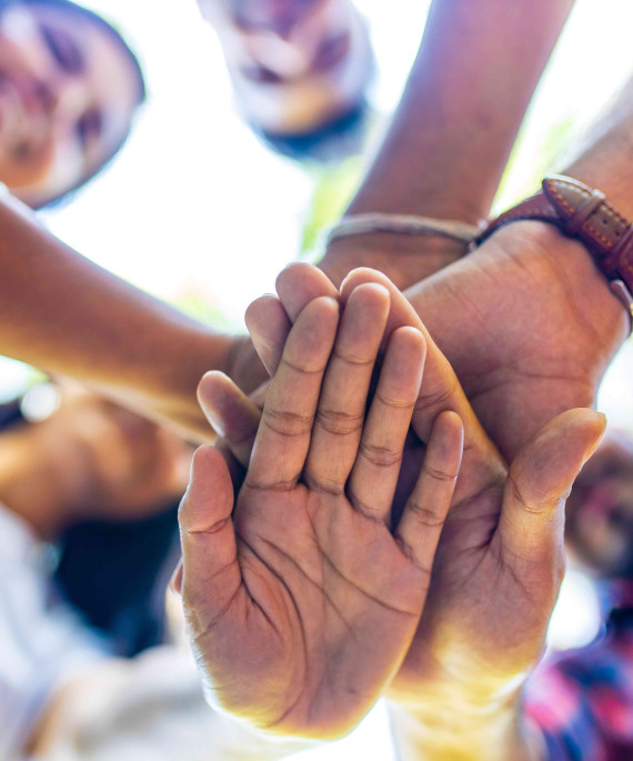 large group of diverse people with their hands out in front together
