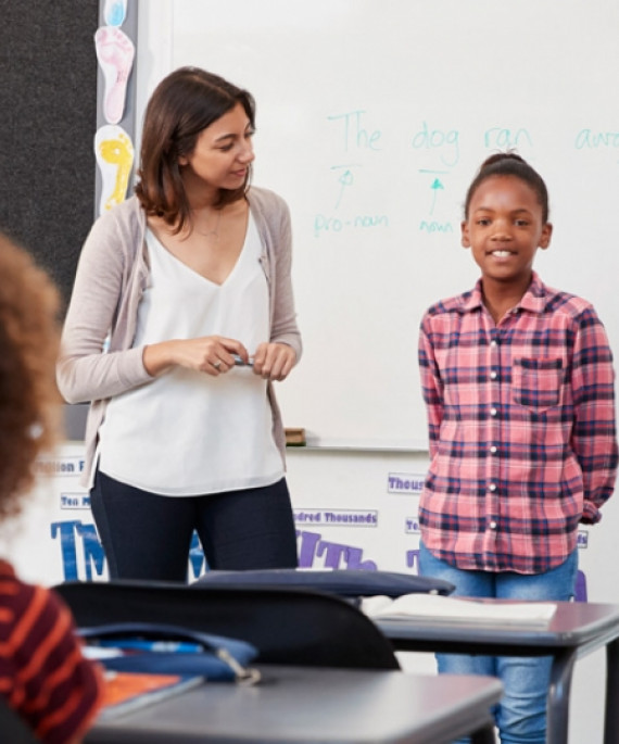 elementary student and teacher in front of class