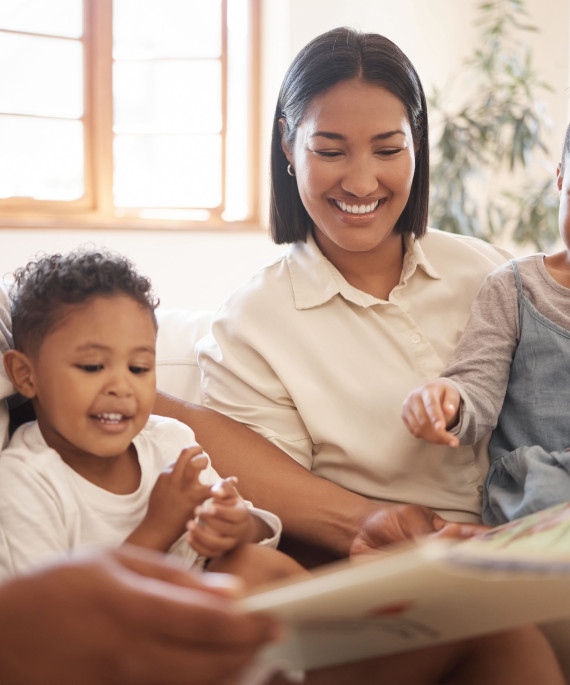Mother and Father reading a picture book to their two young children on their living room couch