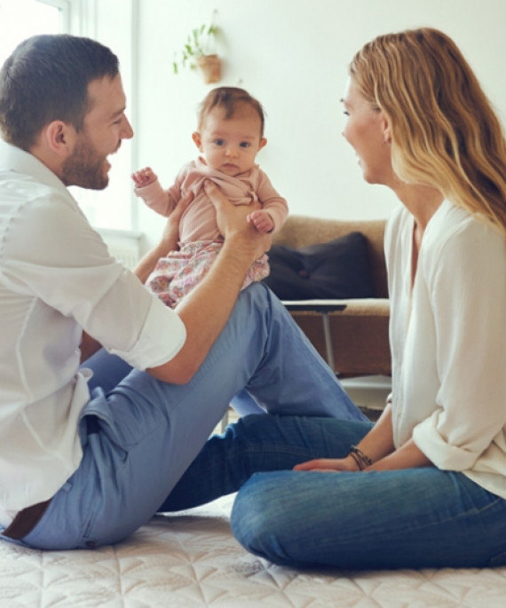 father and mother playing with baby