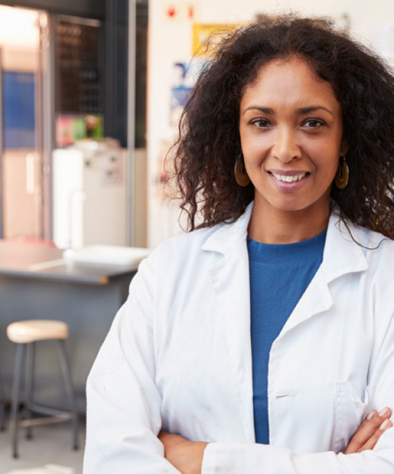 female science teacher in lab coat smiling in school