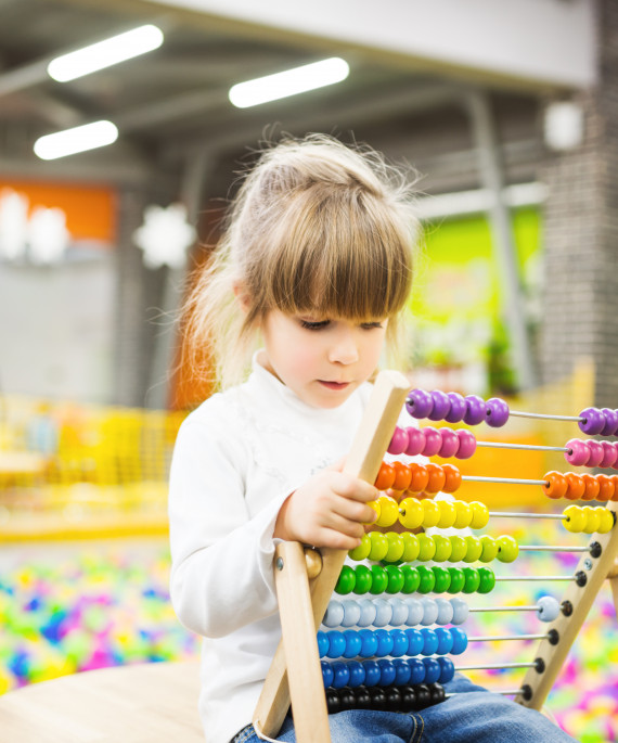 girl playing with a wood abacus toy