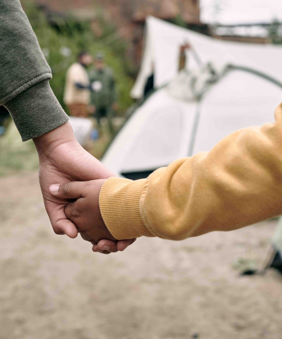 Mother and child holding hands in front of campsite