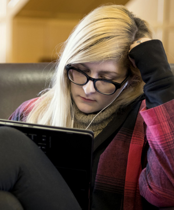 a woman sitting in a chair looking at a laptop