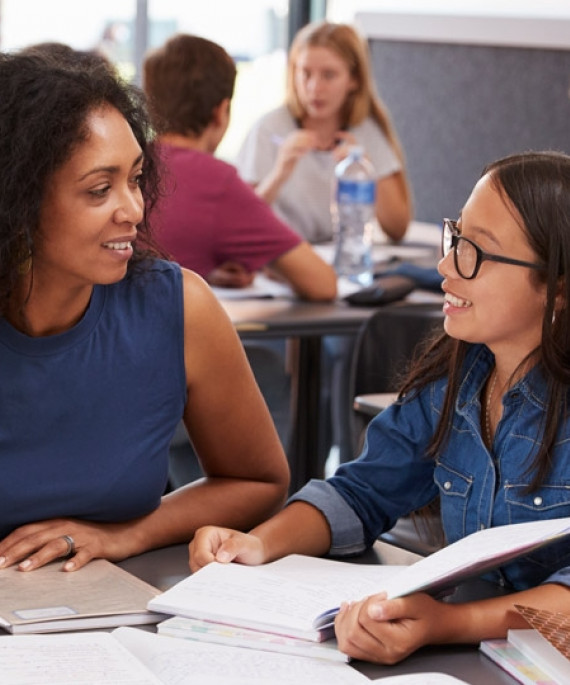 A teacher studying school books in a classroom with students.