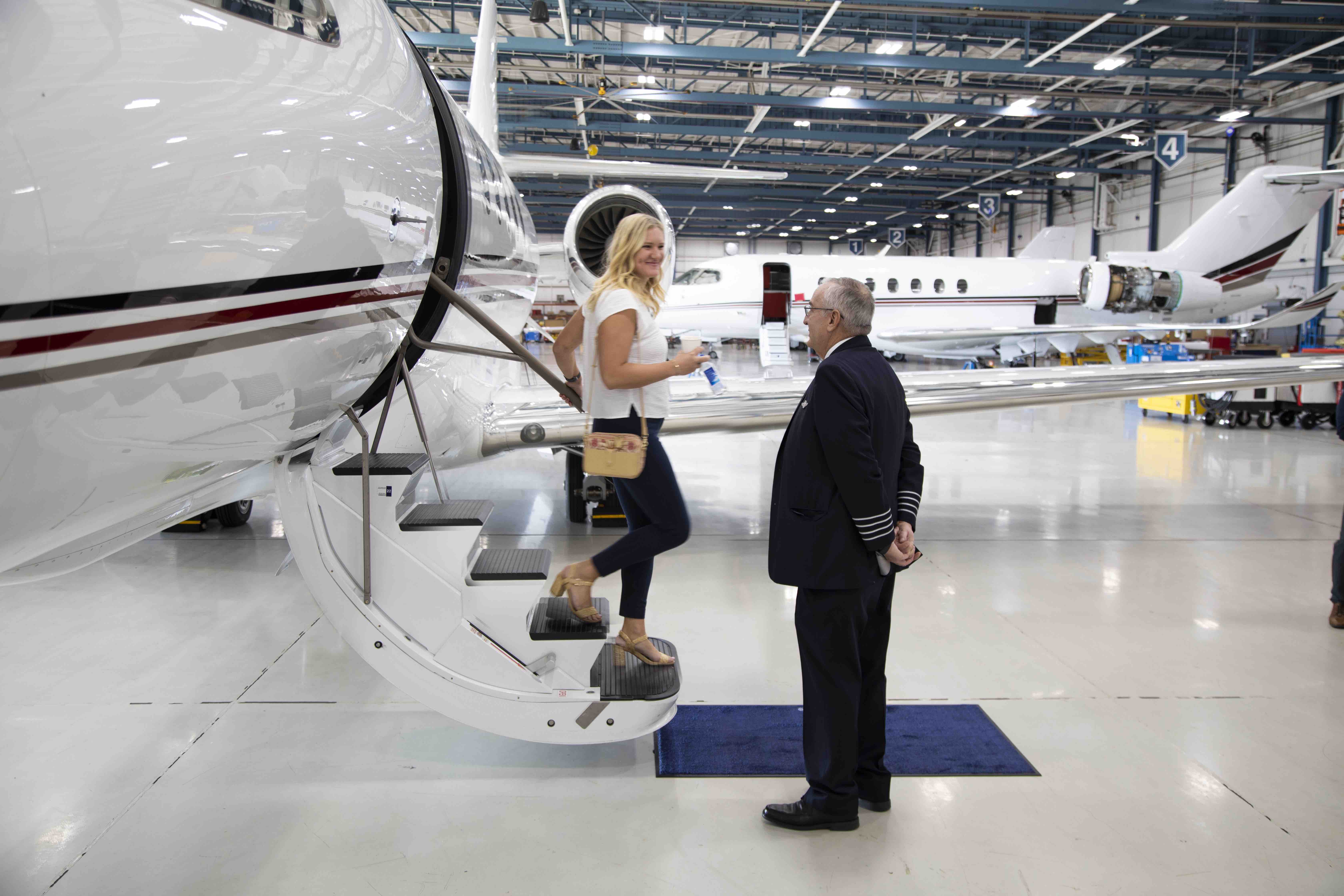 Woman stepping down from NetJet airplain in hanger with pilot